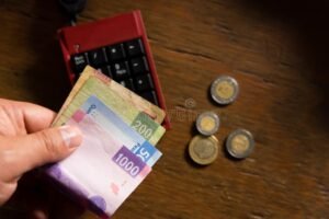 calculadora y dinero mexicano sobre mesa madera