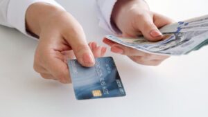 manos sosteniendo billetes y tarjetas bancarias