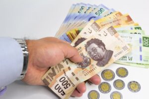 Qué Cuenta Bancaria Ofrece Depósitos Sin Límite en México 4 manos sosteniendo varias monedas y billetes mexicanos