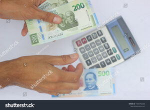 manos usando calculadora con billetes mexicanos