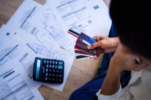 persona pagando deudas con calculadora y billetes