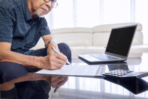 persona rellenando formulario con calculadora y laptop