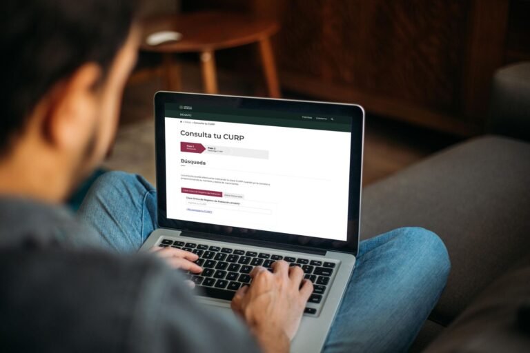 persona usando laptop con curp en pantalla